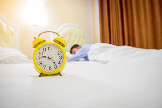 Man sleeping with alarm clock in foreground