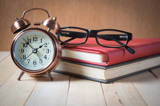 Retro alarm clock and book with glasses.