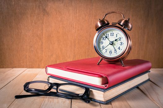 Retro alarm clock and book with glasses.