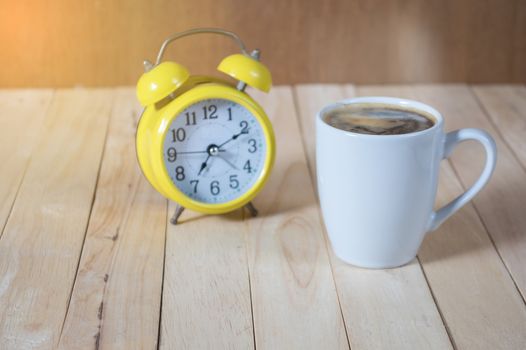 A cup of coffee on the table with  clock.