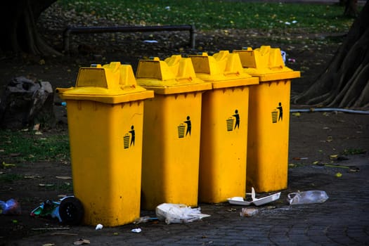 Garbage bins and pile of garbage on floor in park