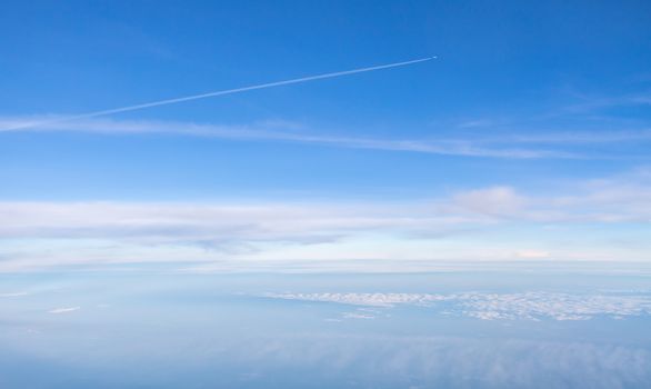 Small plane in the blue, boundless sky above white clouds
