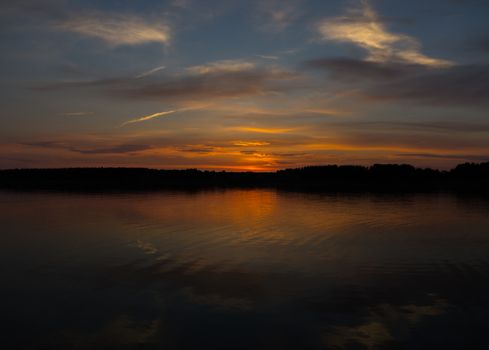 Majestic red sunset on the river bank and its reflection in water