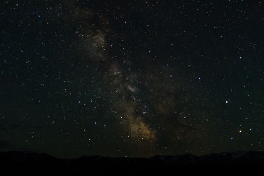 Night mountain landscape with snowy mountain peaks and edges night sky with many stars and milky way on background