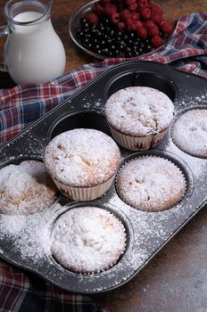 Muffins   sugar powder in the pan on the table with milk and berries