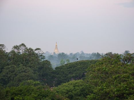 Golden pagoda among the trees and morning mist in Sittwe, the capital of the Rakhine State in Western Myanmar.
