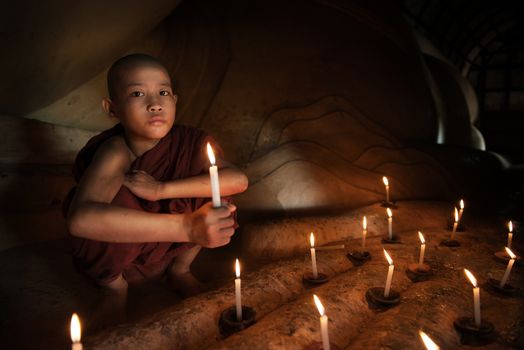 Little novice monk hand holding candlelight inside temple, Bagan, Myanmar.