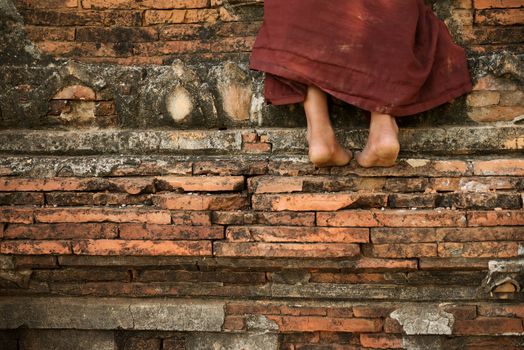 Young novice monk climbing up Buddhist temple, Bagan, Myanmar.