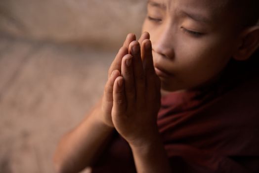 Young novice monk praying inside Buddhist temple, Bagan, Myanmar.