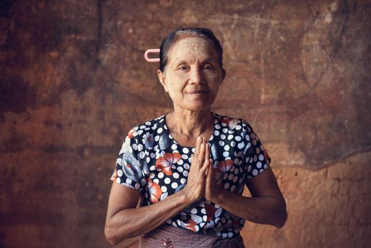 Portrait of traditional Asian Burmese woman praying, standing inside a temple, low light, Bagan, Myanmar