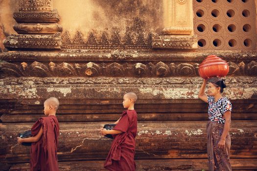 Buddhist novice monks walk to collect alms and offerings at old bagan, Myanmar. This procession is held every morning.
