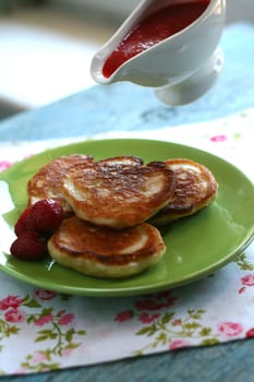 Breakfast serving of pancakes with strawberries and strawberry sauce in a pot in the style of a romantic