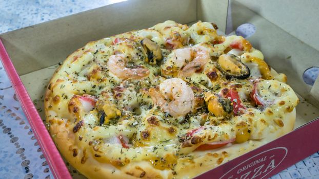 Fresh pizza in cardboard box on  table closeup