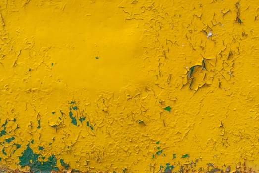 fragment of an iron surface is covered with yellow color paint, which has long been under the influence of different climatic conditions