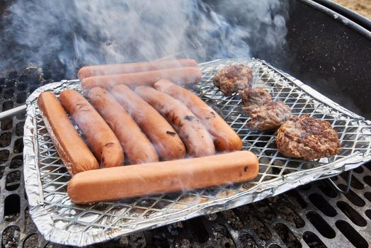 Grilling sausages on a disposable grill outside.