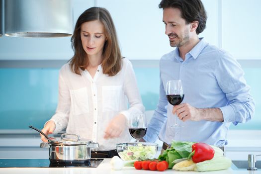 Portrait of a couple having a glass of red wine while cooking dinner