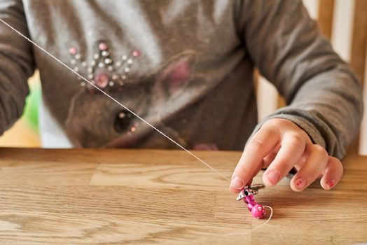 Child playing with beads and a string. Closeup on hands.