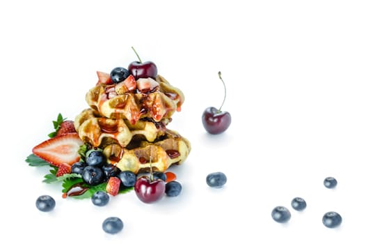 Homemade waffles with strawberry sauce and fresh berries on white background