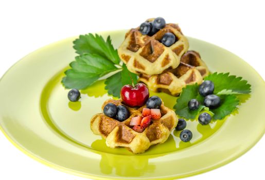Homemade waffles with mix berries fruit on green plate over white background