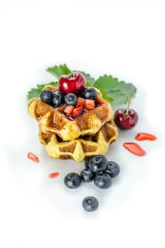 Homemade waffles with strawberry sauce and fresh berries on white background