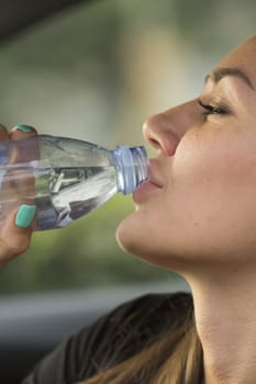 Girl drinks fizzy water from clear plastic bottles.