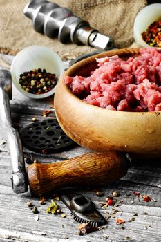 Minced meat and parts of meat grinder on wooden table in rustic style