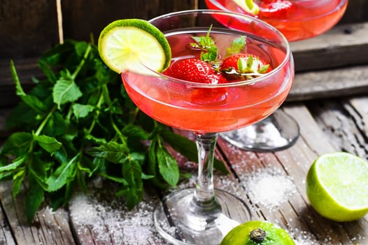 alcohol cocktail in glass on a long stalk with strawberries and lime