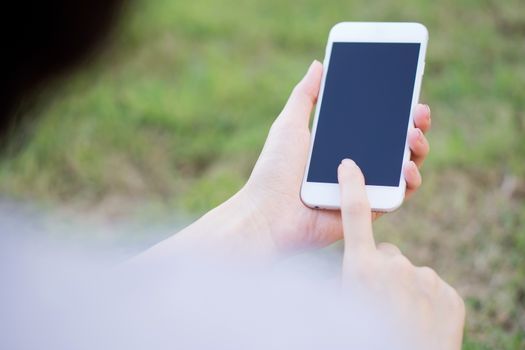 Closeup of female hand using a mobile phone on farm background