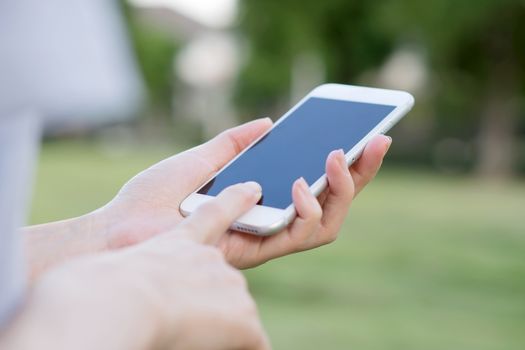 Hands of woman with smartphone in the garden