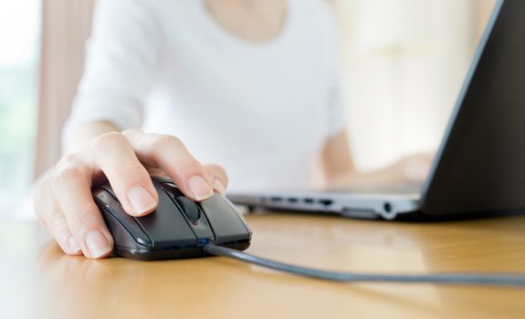 Image of female hands clicking computer mouse
