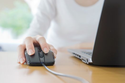 Female hand with computer mouse on table, closeup