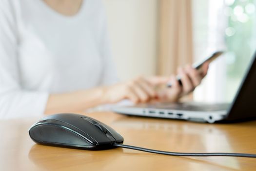 busy young woman is typing on laptop computer and using mobile phone at the same time