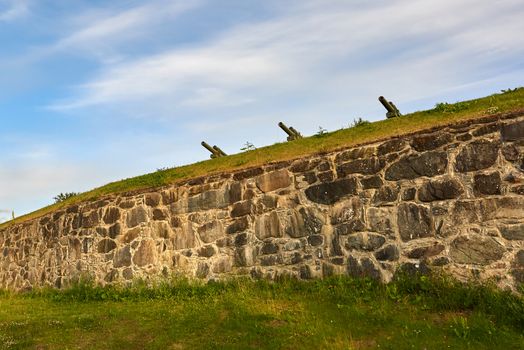 Three iron cannons defending a grassy hilltop.