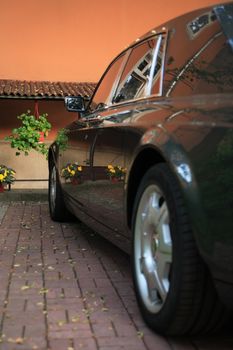 Modern black limousine parking in courtyard near wall