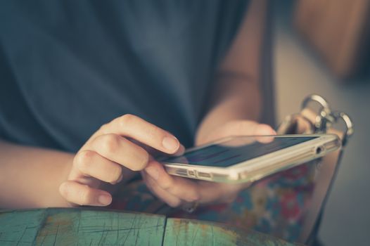 Afternoon scene of young woman using smartphone for social networking in cafe on weekend. Weekend modern lifestyle with technology concept. processed with vintage filter effect