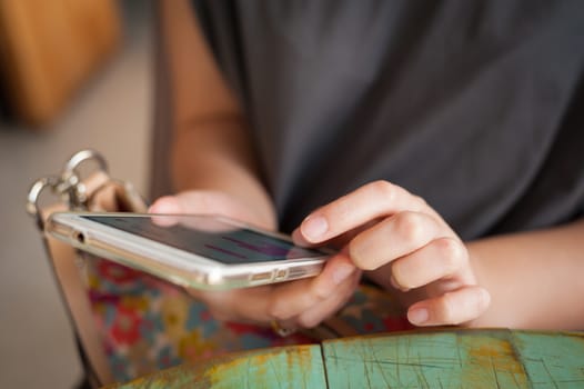 Afternoon scene of young woman using smartphone for social networking in cafe on weekend. Weekend modern lifestyle with technology concept