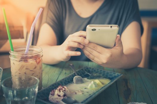 Afternoon scene of young woman using smartphone for social networking in cafe on weekend. Trendy lifestyle concept with technology. processed with vintage filter effect