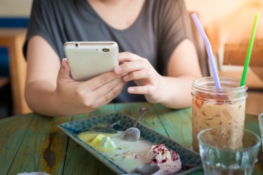 Afternoon scene of young woman using smartphone for social networking in cafe on weekend. Trendy lifestyle concept with technology.