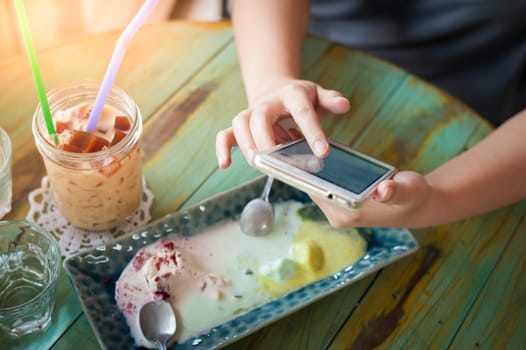 Afternoon scene of young woman using smartphone for social networking in cafe on weekend. Trendy lifestyle concept with technology.