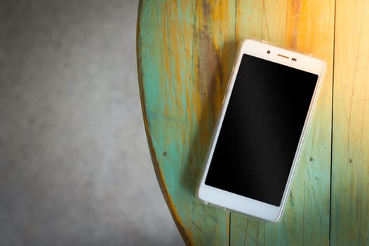 Smartphone with blank area on touch screen on wood table in afternoon time at cafe