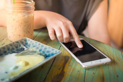 Woman hand touching on smartphone screen in cafe on weekend afternoon