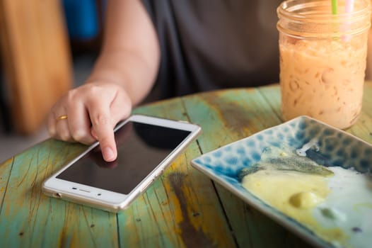 Woman right hand touching on smartphone screen in cafe on weekend afternoon. Trendy lifestyle concept with technology