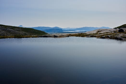 Small pond with view of mountains in the distance.