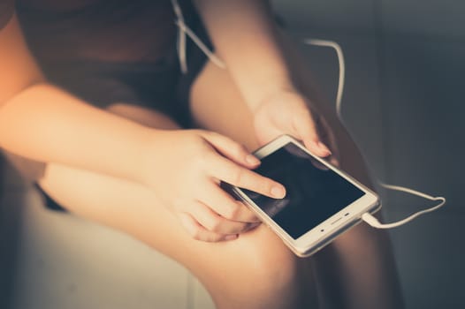 Young woman touching on smartphone screen while listening music in morning time on weekend. Morning lifestyle with technology on weekend concept with vintage filter effect