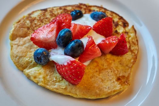 Healthy pancake made from cottage cheese with fresh blueberry and strawberries.