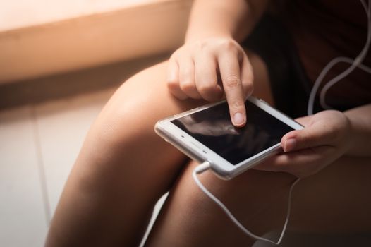 Young woman touching on smartphone screen while listening music in morning time on weekend. Morning lifestyle with technology on weekend concept.