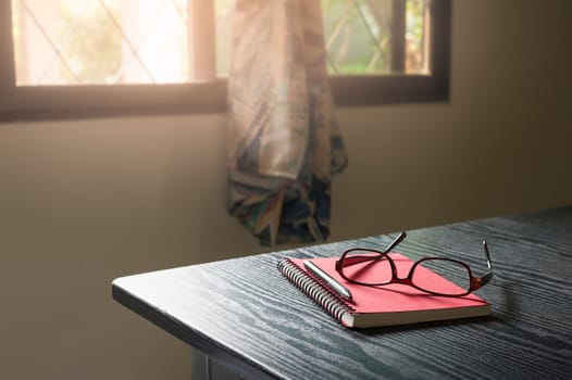 Notebook, pen, and glasses on working table in morning time on work day. Freelance business working concept
