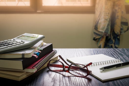 Glasses put down on table beside notebooks and pen in morning time on work day. Freelance business working concept