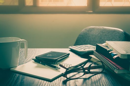 Smartphone put down on table beside notebooks and pen in morning time on work day. Business working at home concept with vintage filter effect