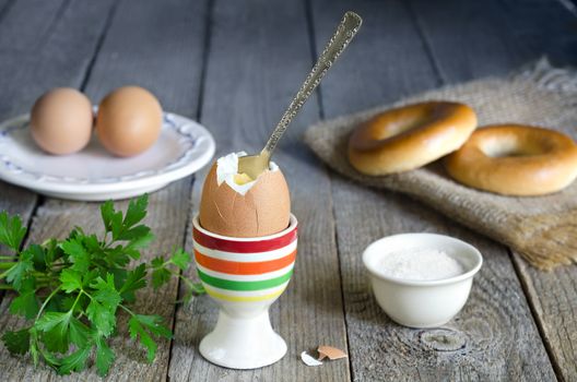 Egg stand with spoon, parsley,salt. Eggs in plate and donut on the burlap,old boards on the village.